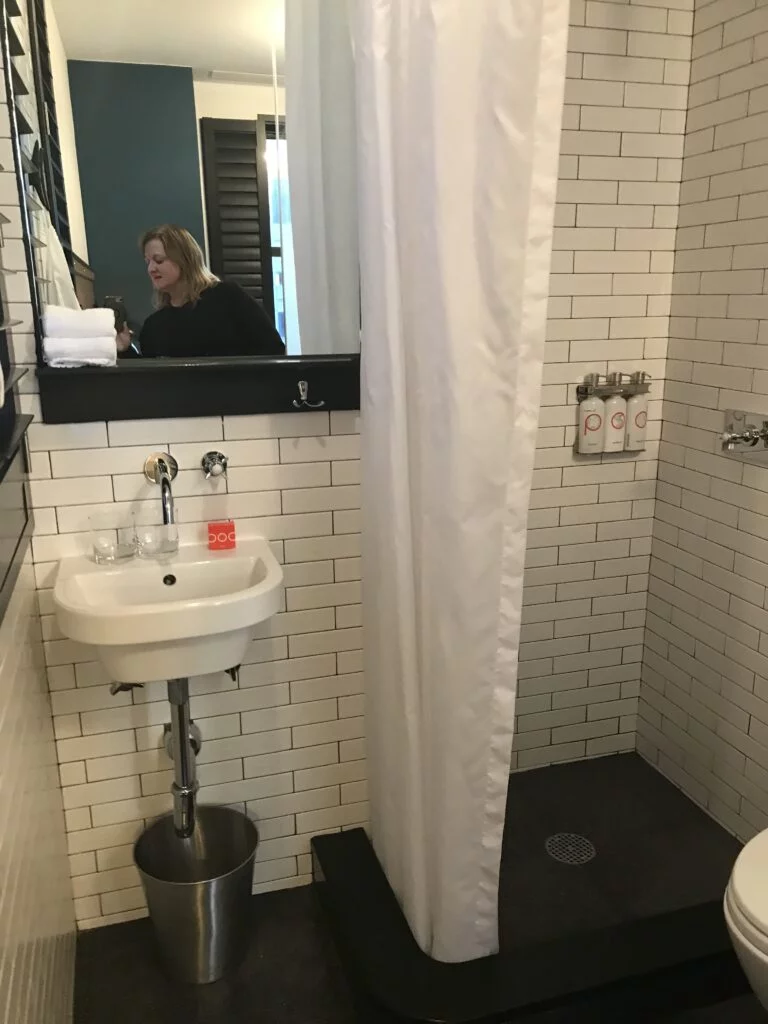 Pod 39 Bathroom: Close-up of the small bathroom area with a sink and shower, featuring a clean and efficient layout.