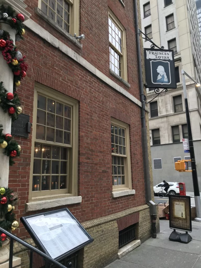 Brick exterior of Fraunces Tavern with flag and lanterns in the Financial District