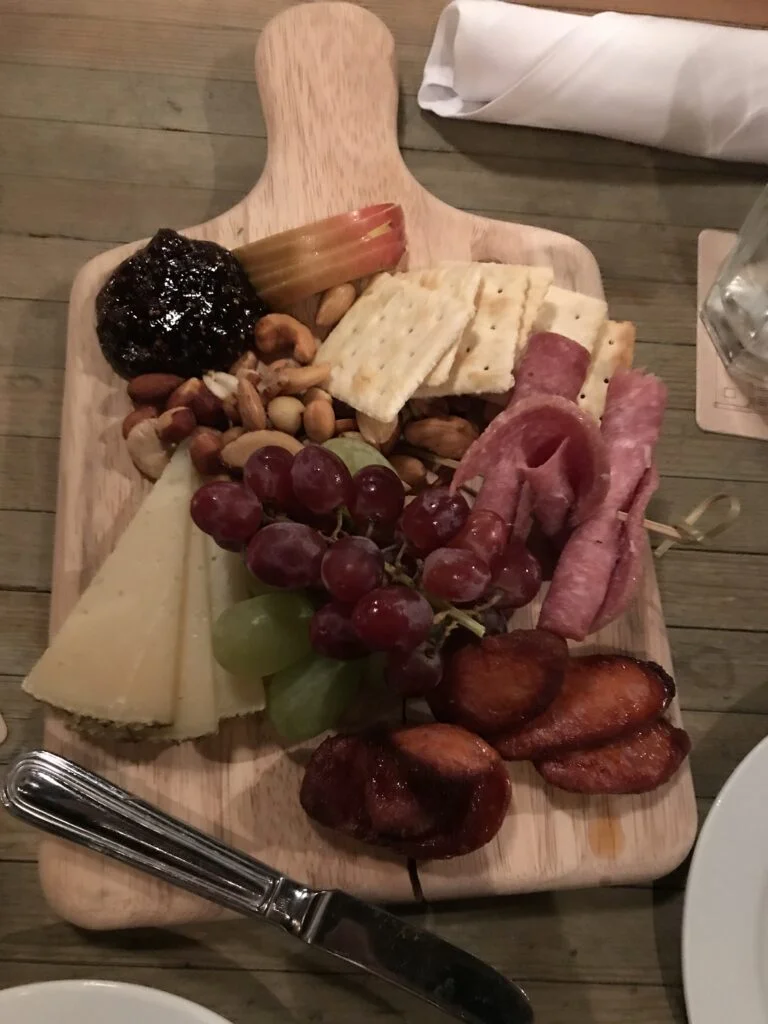 Charcuterie board with cheeses, meats, and pickles on a wooden table at Fraunces Tavern