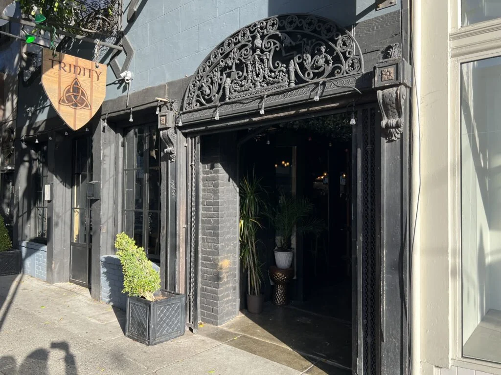 Entrance of Trinity Irish Bar featuring a small tree.
