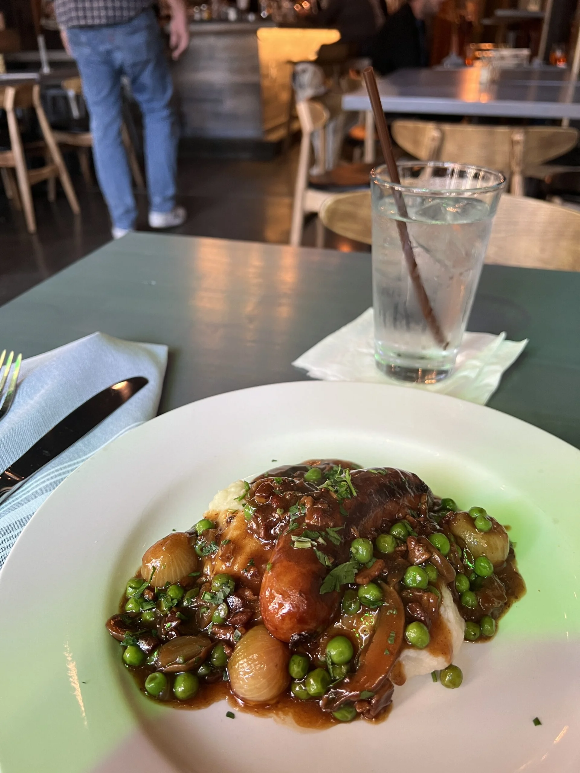 Plate of Bangers and Mash at Trinity Irish Bar with a dog in the background.