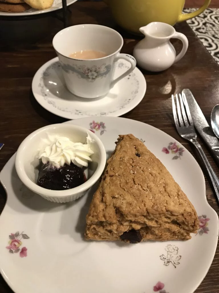 Solo high tea for one with scone, sandwich, and a pot of tea on mismatched china