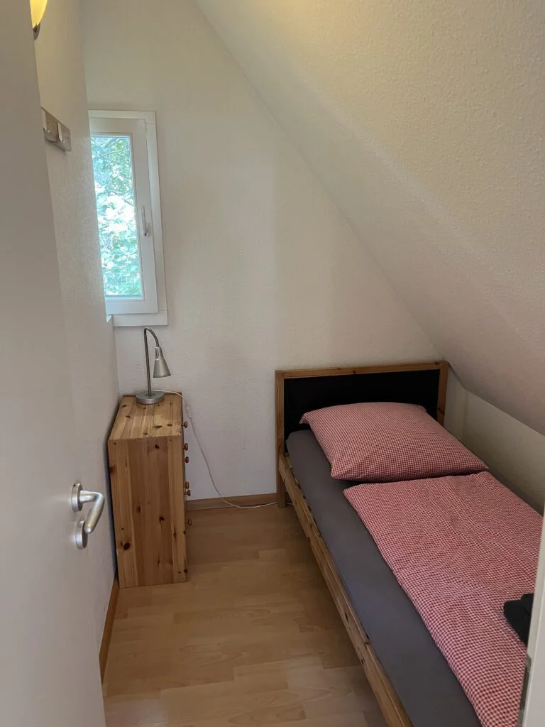 Black Forest Bike Hostel Single Bedroom: A compact single bedroom at the Black Forest Bike Hostel, furnished with a bed and minimalistic decor.