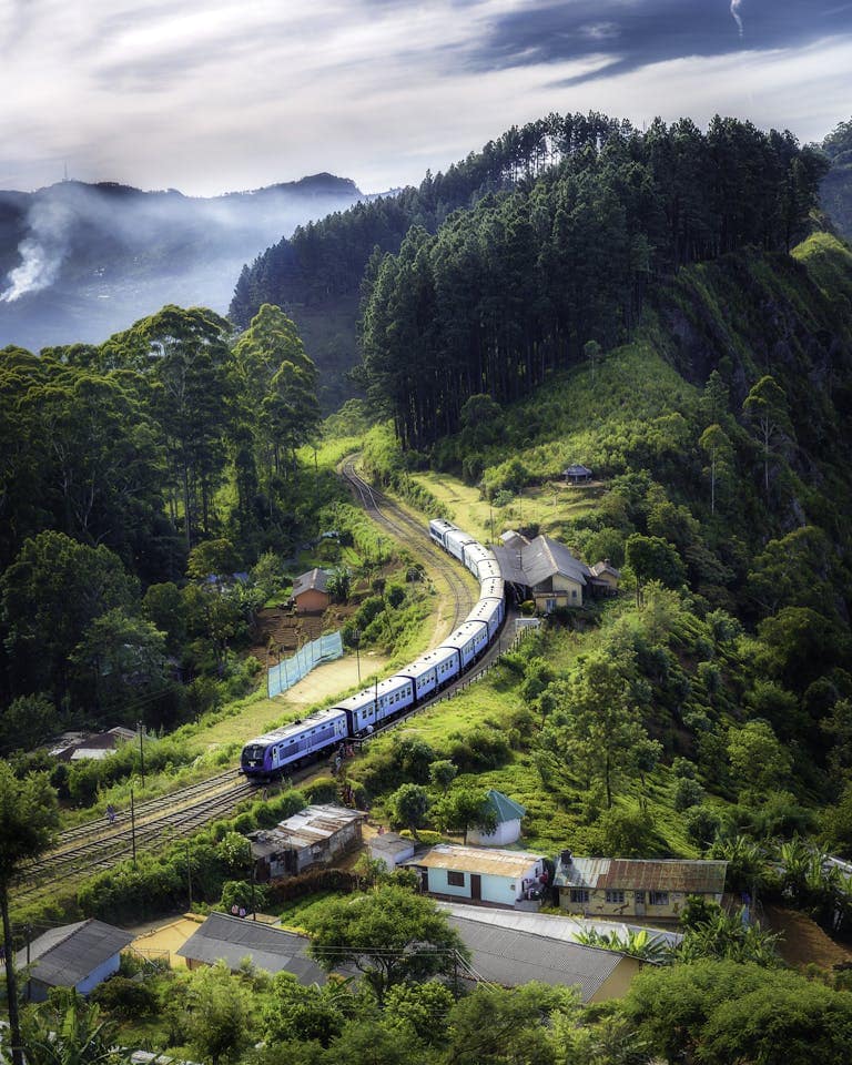 Planning Your California Zephyr Experience: Best Stops and Cool Hotels 32 Aerial view of a picturesque train winding through lush green hills and rural houses.