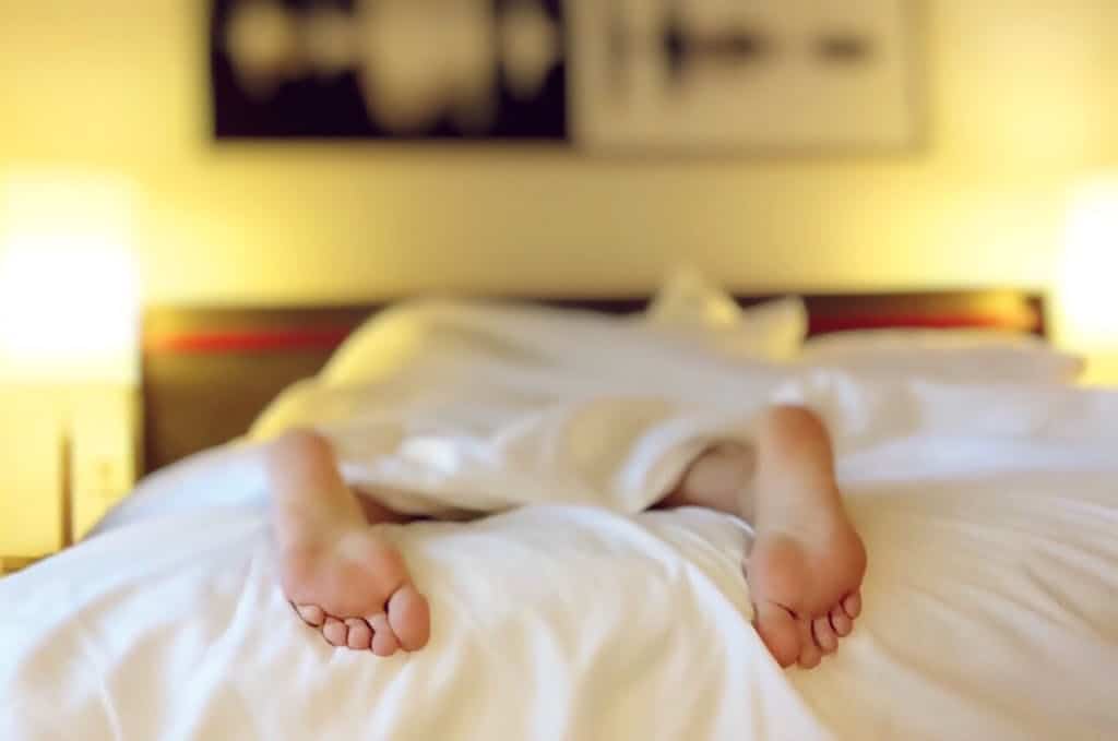 10 Travel Lessons I Just Learned in Europe (and What I’ll Do Differently Next Time) 4 A person relaxing on a bed with feet under white sheets with feet sticking out.