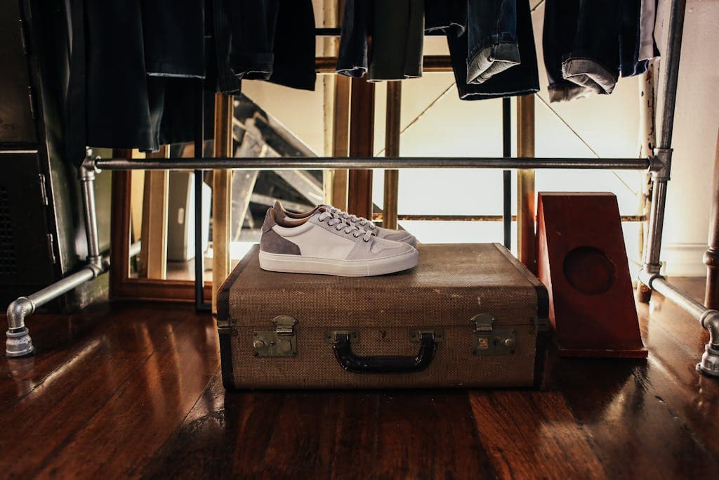 10 Travel Lessons I Just Learned in Europe (and What I’ll Do Differently Next Time) 3 White sneakers resting on a vintage suitcase in a warmly lit room, invoking a retro vibe.