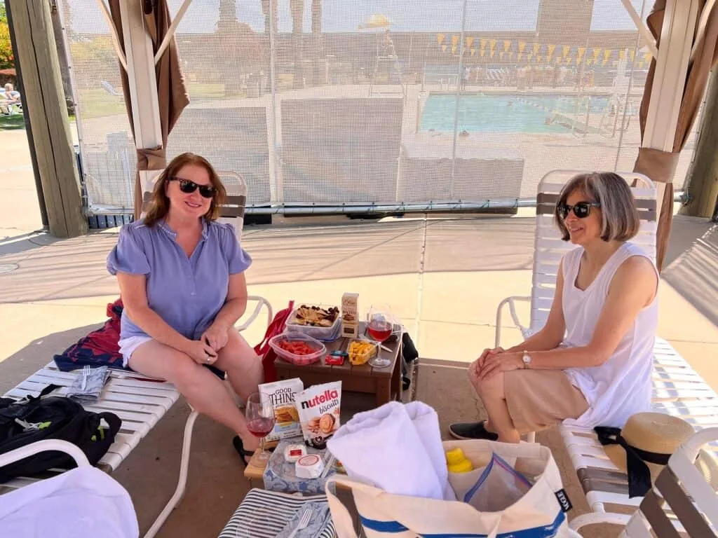 Friends seated in the cabana with the food spread on the table between them