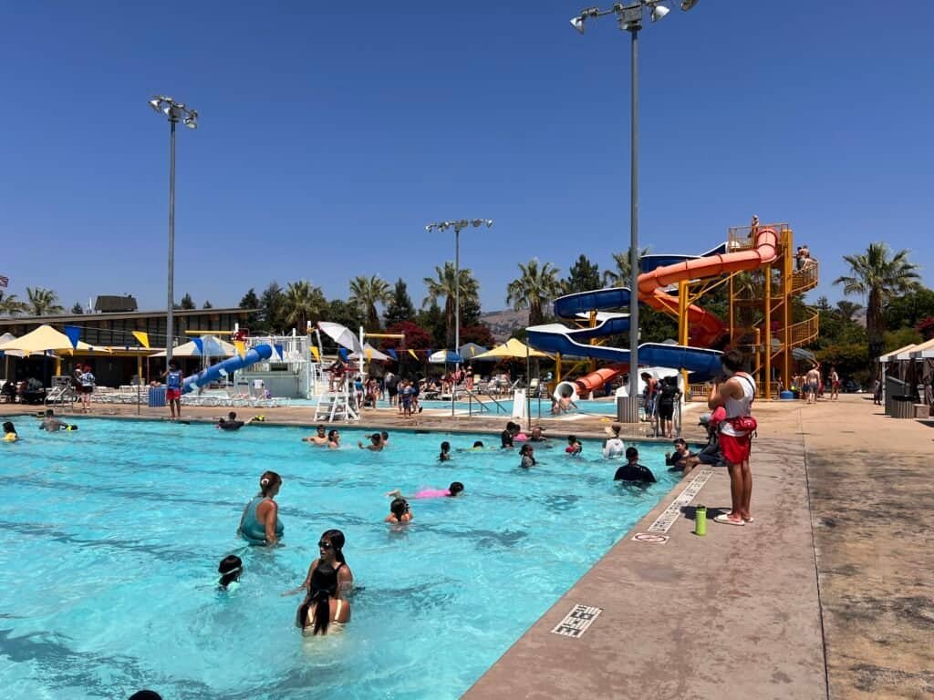 Recreation pool with water features and slides full of children